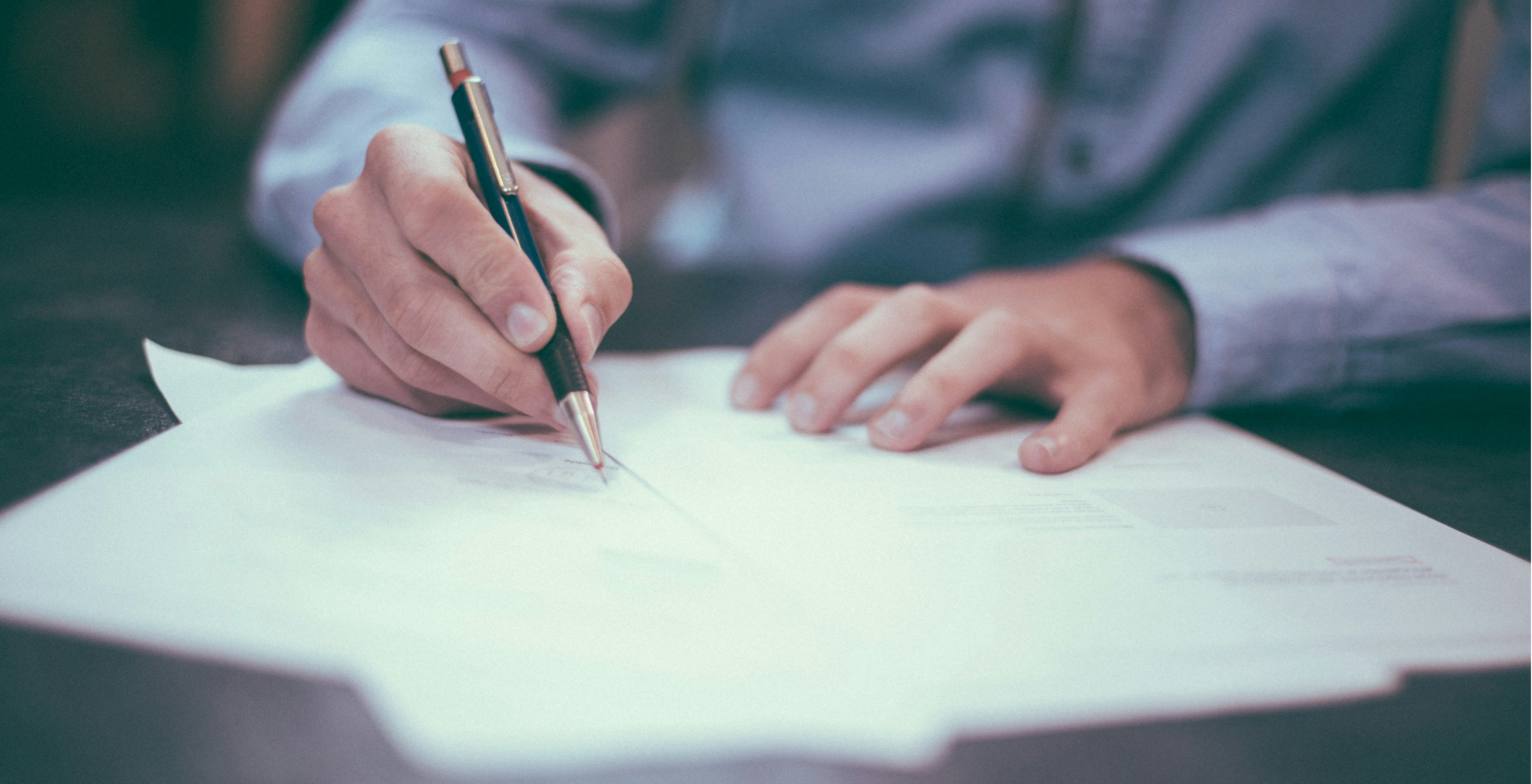 Persona firmando un documento sobre un escritorio